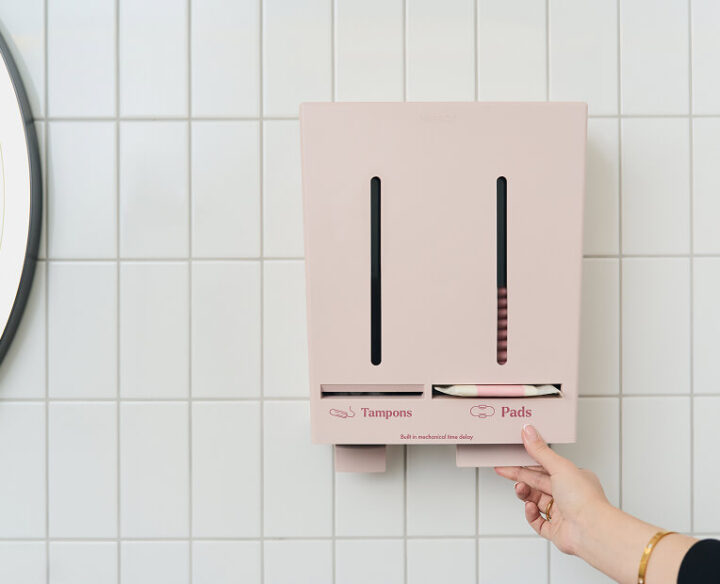 Närbild på Herbox automat där en hand tar en binda från automaten.