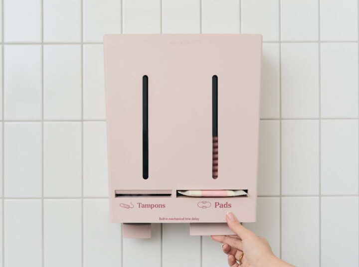 Närbild på Herbox automat där en hand tar en binda från automaten.