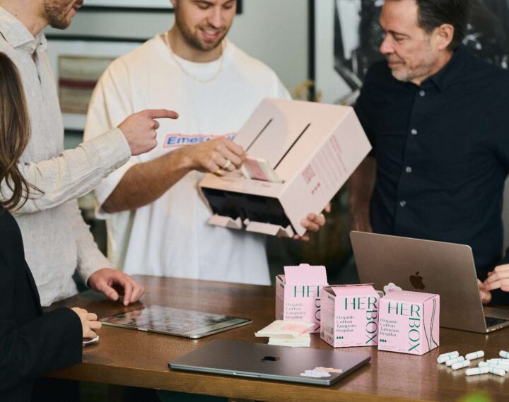 Grupp visar upp Herbox mensskyddsautomat och produkter vid ett bord