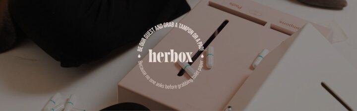 Automat med tamponger och bindor, med texten "herbox" och uppmaning att ta en produkt.