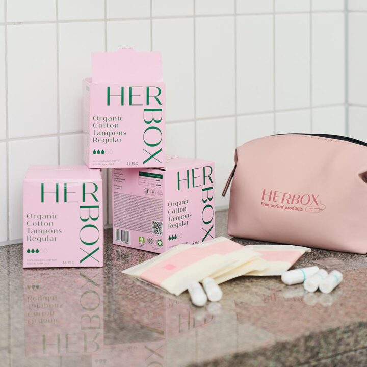 Bild på Herbox produkter, tamponger i storlek regular 56 pack, en rosa Herbox necessär och några lösa bindor och tamponger i ett vitt badrum.