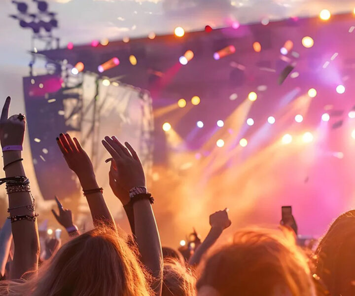 Concert scene with colourful stage lights and crowd raising hands.