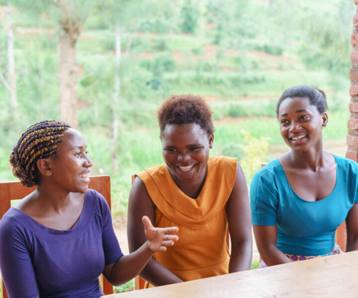Tre kvinnor i samtal i grönskande miljö i Rwanda, symbol för Herbox sociala hållbarhetsarbete