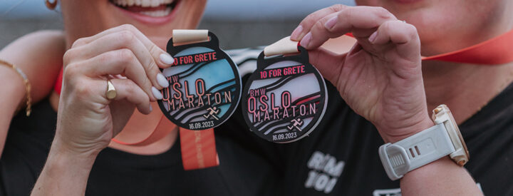 Två tjejer visar upp deltagarmedaljer från Oslo Marathon 2023, Herbox sponsrade loppet vid tidpunkten.