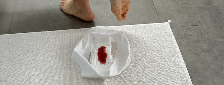 Person utan strumpor på en matta bredvid en binda med mens.