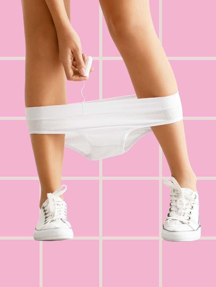Person i vita skor och underkläder, håller en tampong. Rosa rutad bakgrund.
